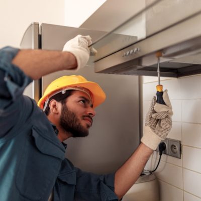 Service man repairing kitchen extractor, replacing filter in cooker hood. High quality photo