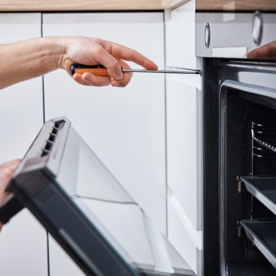 Appliance repair. Man installing electricity oven in the kitchen