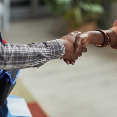 Close up of unrecognizable African-American woman shaking hands with handyman standing in home interior, copy space